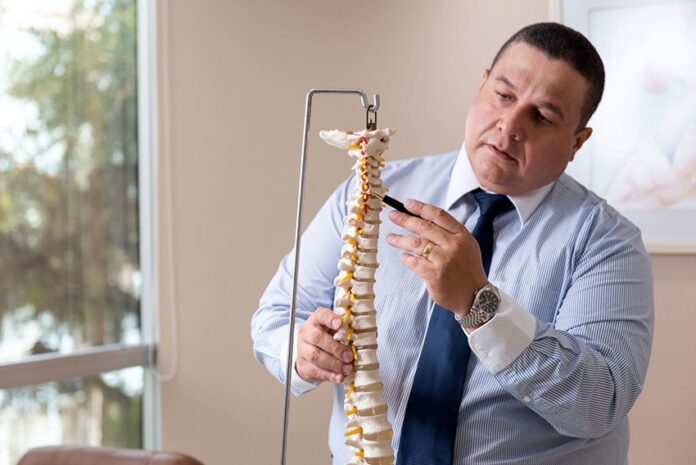 O neuro-ortopedista Luiz Felipe Carvalho aponta para um modelo de coluna vertebral. Foto DivulgaçãoDandi Albuquerque